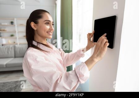 Woman using smart wall home control system Stock Photo