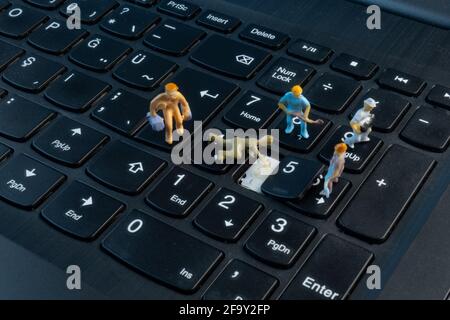 Mini Workers working on button on top of keyboard Stock Photo