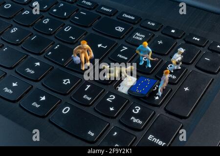 Mini Workers working on EU flag on top of keyboard Stock Photo
