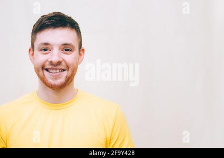 Young man in yellow t-shirt smiling on gray background Stock Photo