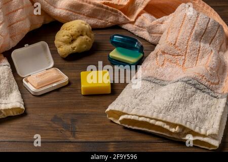 Composition of scented soaps of various colors and shapes with towel and natural sponge, on wooden table Stock Photo
