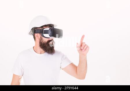 Man with beard in protective helmet using digital touch screen. Brutal bearded construction boss wearing VR headset isolated on white background Stock Photo