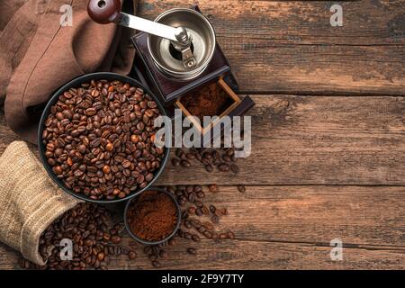 Coffee beans in a black plate and bag, coffee grinder on a wooden brown background. Top view with copy space. Stock Photo