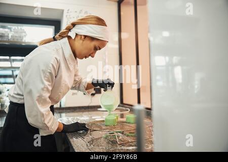 Focused woman in chef uniform making dessert Stock Photo