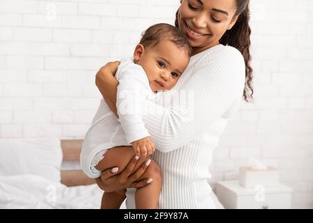 African Mommy Hugging Baby Son Carrying Him In Arms Indoors Stock Photo