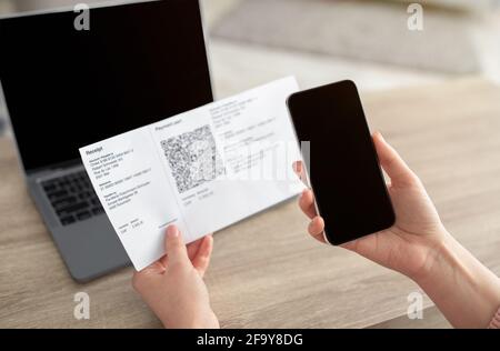 Woman using mobile phone to scan the QR code for the bill through the app, smartphone with blank screen. Stock Photo