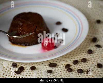 Closeup spoonful of a Coffee Flan on a plate decorated with a cherry and coffee beans Stock Photo