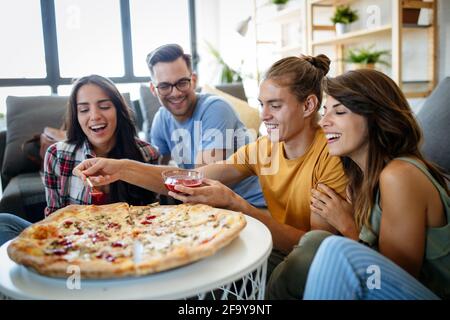 Group of friends are having party at home, eating pizza and having fun. Stock Photo
