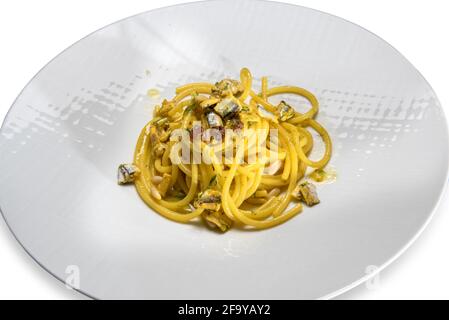 Spaghetti pasta with sardines - Sicilian recipe with raisins, pine nuts and fennel, close up in white dish isolated on white Stock Photo