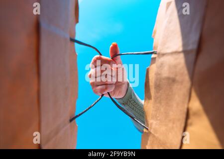 Woman hand holding paper shopping bag. View from inside. Food take away concept Stock Photo