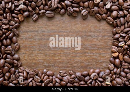 Coffee frame. A border made up of coffee beans around a wood effect background Stock Photo