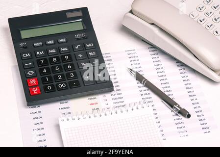 Calculator, financial documents with numbers and a notepad on the desktop. Pen and telephone. Planning concept, budgeting. Work from home or office. Stock Photo