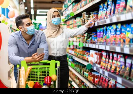 Muslim Couple Choosing Food In Supermarket Doing Grocery Shopping Together Stock Photo