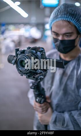Young operator in medical protective suit with camera Stock Photo