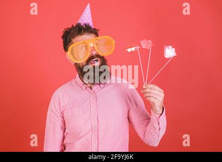 Emotional diversity concept. Guy in party hat celebrate, posing with photo props. Hipster in giant sunglasses celebrating. Man with beard on cheerful Stock Photo