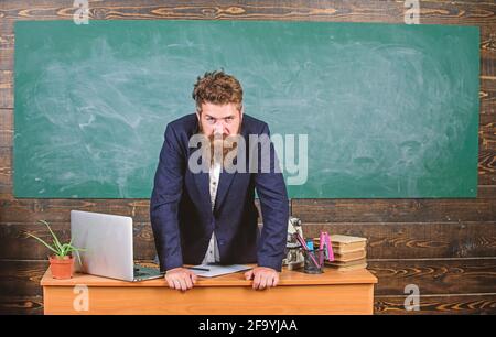 Teacher strict serious bearded man lean on table chalkboard background. Teacher looks threatening. School principal threatening with punishment. Rules Stock Photo