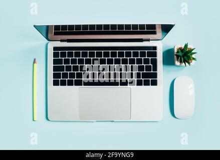 top view of laptop, computer mouse, pencil and cactus on blue background Stock Photo