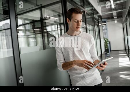 young student standing in hall and using digital tablet Stock Photo