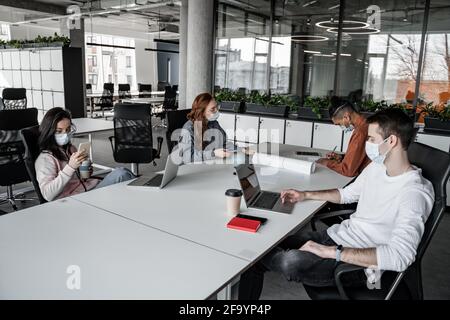 interracial students using gadgets while sitting at desk Stock Photo