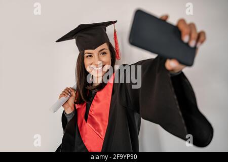 happy student in graduation cap and gown taking selfie, senior 2021 Stock Photo