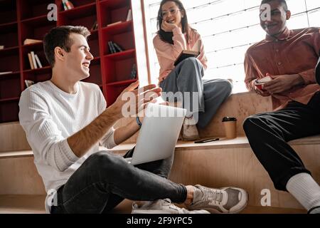 happy interracial students smiling while sitting on stairs, senior 2021 Stock Photo