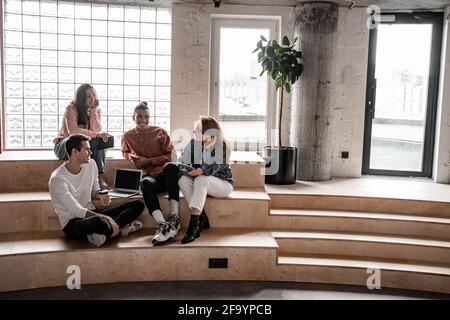 interracial students smiling while sitting on stairs Stock Photo