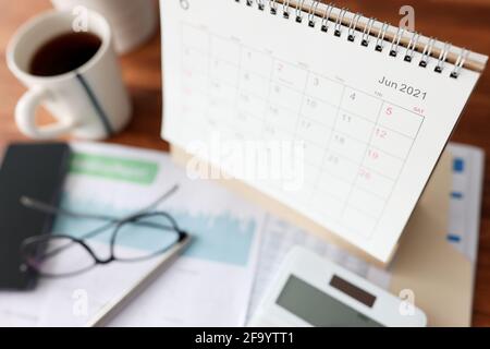 Calendar for June calculator and cup of tea is on table Stock Photo