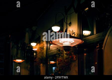 terrace outdoor heater pendant and round lanterns lighting illuminate the night backyard with decorative dried flowers on the wall night scene. Stock Photo