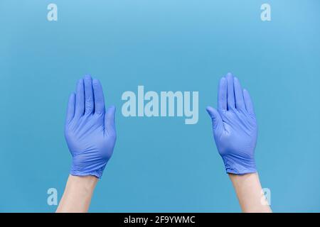 Close up of male hands in medical protective latex gloves snaps her fingers to music rhythm gesture, isolated over blue studio background Stock Photo
