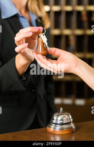 Reception - Guest checking in a hotel at the front desk, the room key is handed over Stock Photo