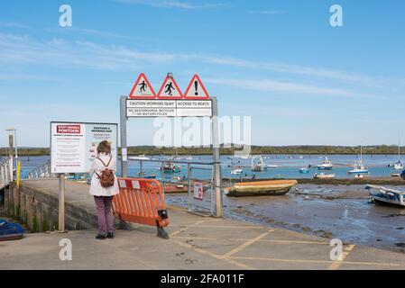 West Mersea Pier, rear view of a woman reading the noticeboard at the entrance to West Mersea Pier, Mersea Island, Essex, England, UK. Stock Photo