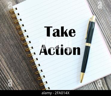 Top view of a pen with Take Action written on a notebook. Stock Photo