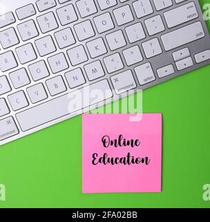 Online education written on a pink sticky note. Stock Photo