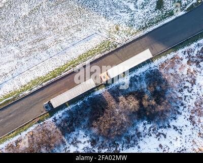 Aerial Follow Shot of White Semi Truck with Cargo Trailer Attached Moving Through Industrial Warehouse, Rural Area. Stock Photo