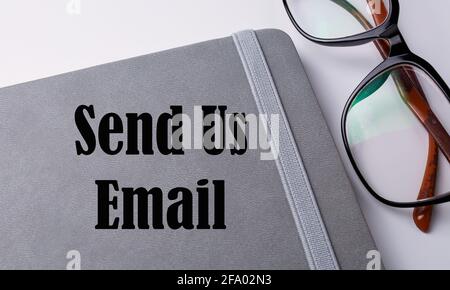 Send us email written on a notebook. Stock Photo