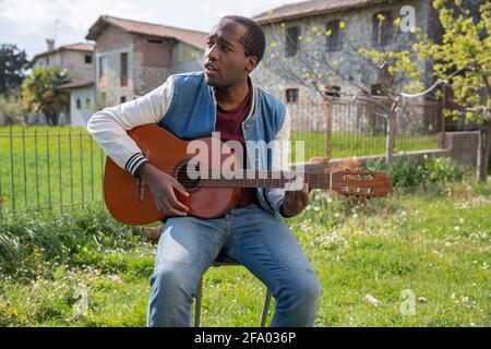 Young artist plays the guitar outdoors and sings Stock Photo