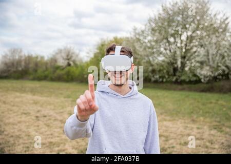 A guy in a field is having fun while using some VR headsets outdoor in a field. Stock Photo