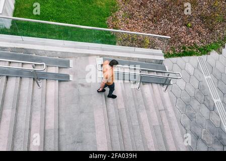 The man comes down the stairs. Concrete staircase with railings and green grass. Urban interior. View from above. Stock Photo