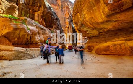 Group of people between sandstone rocks at narrow path in Petra, Jordan Stock Photo