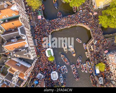 Canal boat parade on Koningsdag Kings day festivities in Amsterdam. Birthday of the king. Seen from helicopter. Stock Photo