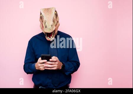 man in dinosaur mask using smartphone Stock Photo