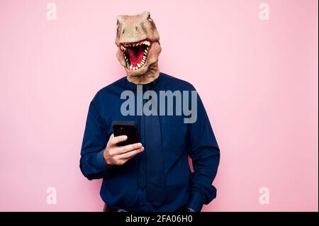 man in dinosaur mask using smartphone Stock Photo