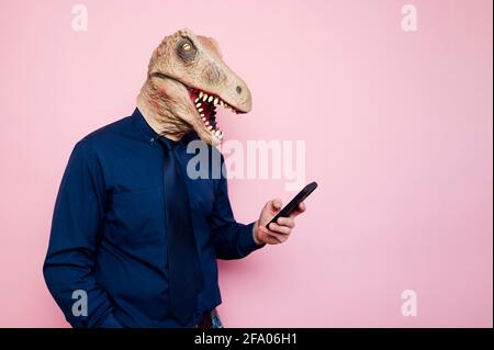 man in dinosaur mask using smartphone Stock Photo