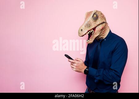 man in dinosaur mask using smartphone Stock Photo