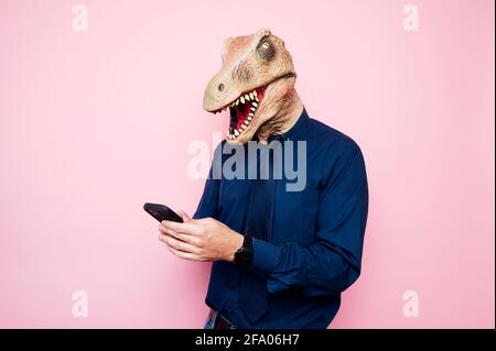 man in dinosaur mask using smartphone Stock Photo