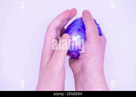 Close up of game with two-color blue and pink slime in someone's hands on a white background. The mucus is crushed, stretched, torn and squeezed by ha Stock Photo