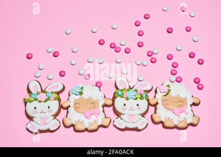 Pink pastel background with homemade gingerbread in form of cute rabbit and lamb. Tasty biscuits covered with colorful glaze. Easter concept. Stock Photo