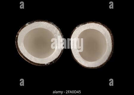 Coconut divided into two equal parts, view from the top, on a black background Stock Photo