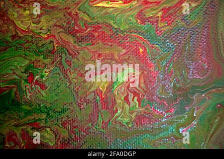 Canvas picture marbled with acrylic paint in the colors red, green and yellow. Stock Photo