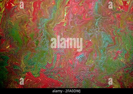 Canvas picture marbled with acrylic paint in the colors red, green and yellow. Stock Photo